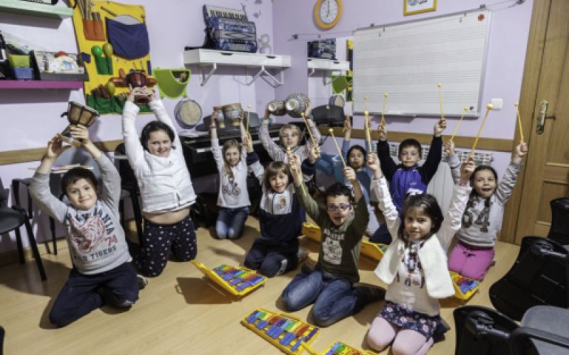 Aula de musica con niños sentados con instrumentos de percusión