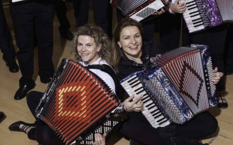 Grupo de personas con acordeón y dos chicas sentadas en el suelo