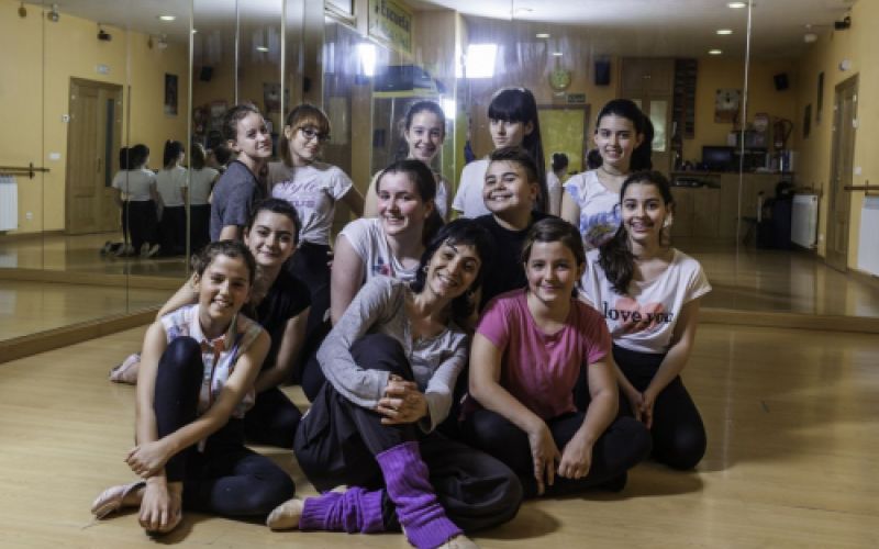 Grupo de niños sentados en aula de danza junto a profesora